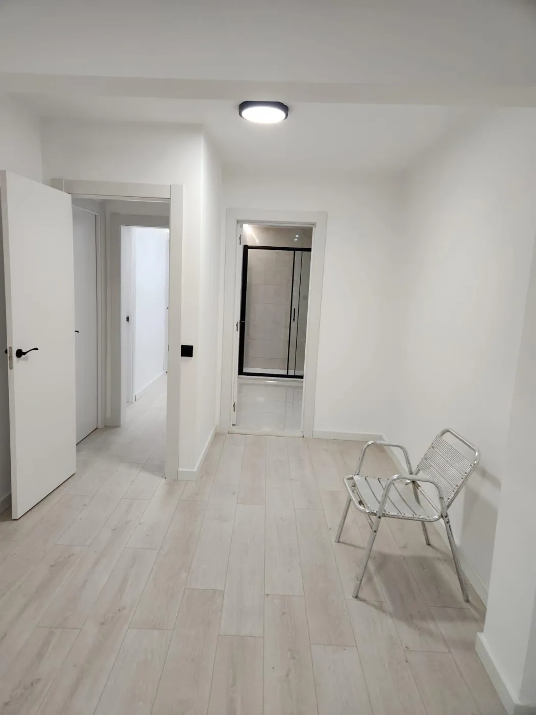 Pasillo de vivienda reformada con suelo claro y puertas blancas