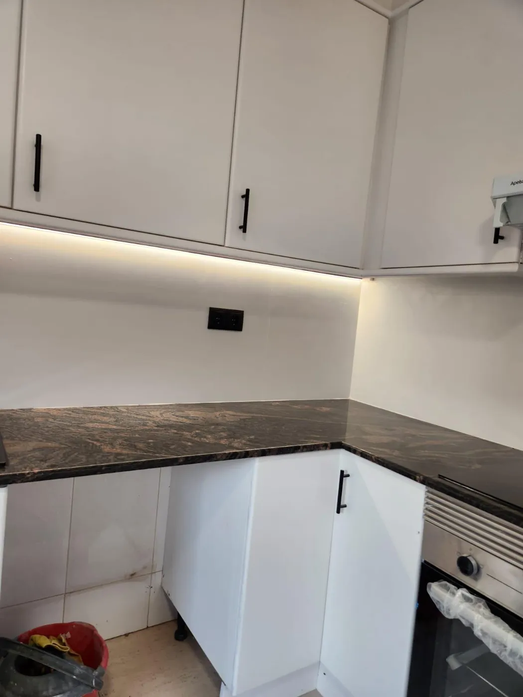 Cocina en esquina con iluminación LED bajo muebles altos